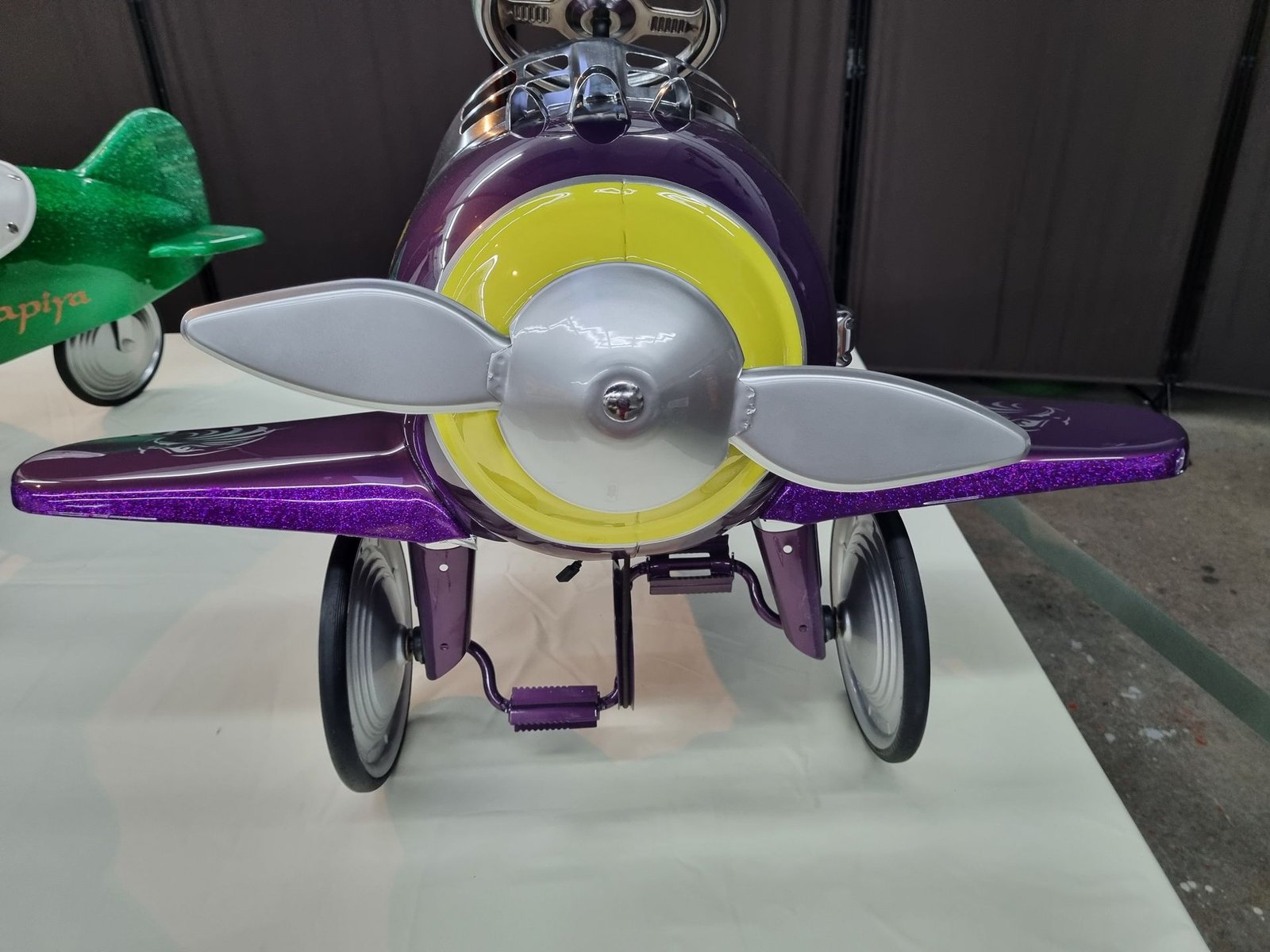 Ein lila Spielzeugflugzeug mit einem gelben Propeller steht auf einem Tisch